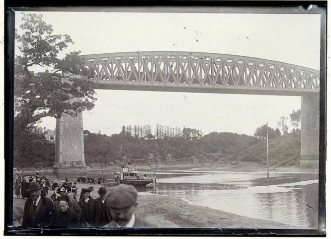 [Pont ferroviaire enjambant un cours d'eau : vue d'ensemble sur l'ouvrage, au premier plan des promeneurs longeant la rive] / [cliché de Joseph Bellec].
[ca 1905]